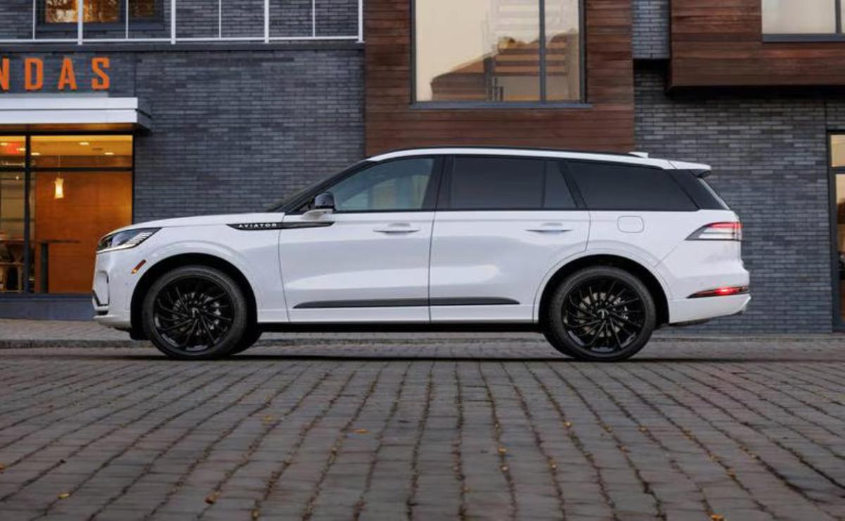 White luxury SUV parked on cobblestone street beside modern building.