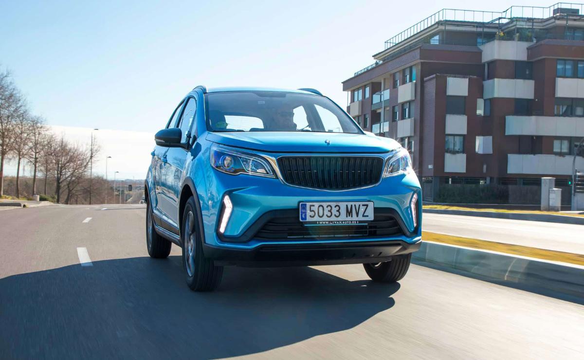 Blue compact SUV driving on a city street under clear skies.