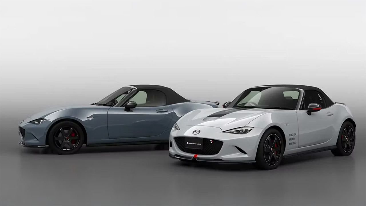 Two Mazda MX-5 Miata sports cars, one blue and one white, side by side in a studio.