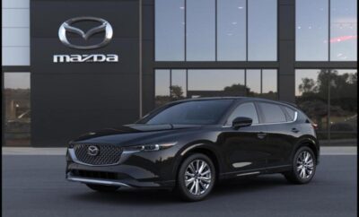 Sleek black Mazda SUV parked outside a showroom at dusk.