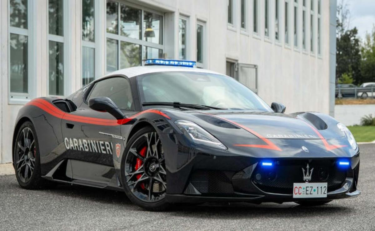 A sleek black police car with flashing blue lights parked by a building.
