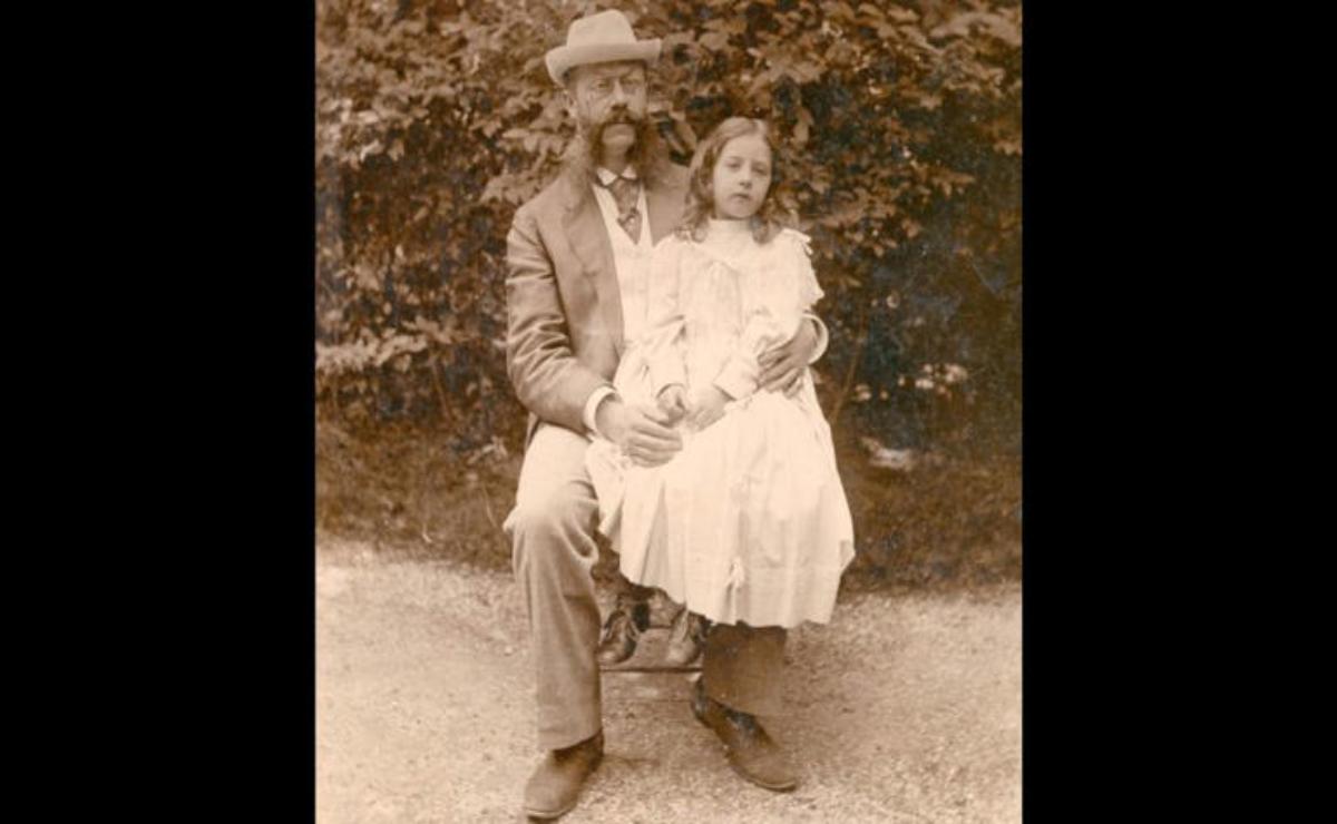 A vintage photo of a man and girl sitting together outdoors.