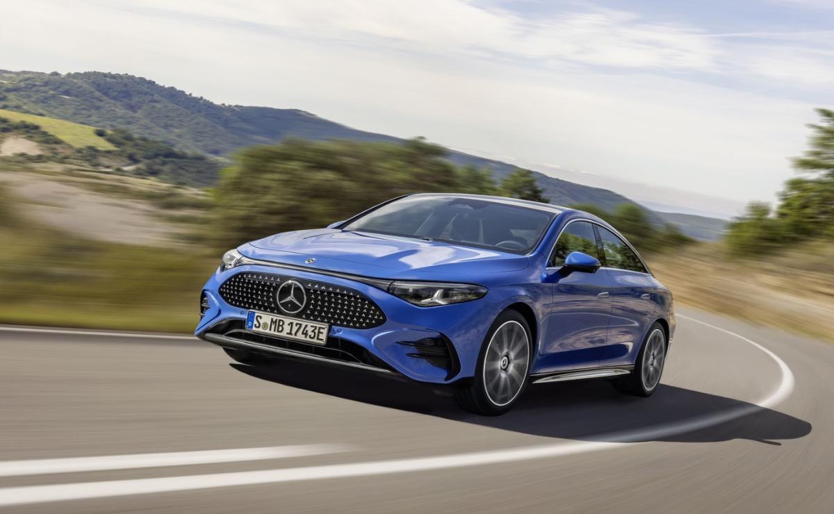 A blue Mercedes-Benz coupe driving on a scenic road.