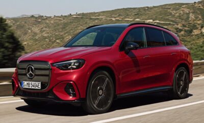 A sleek red luxury SUV driving on a scenic road.