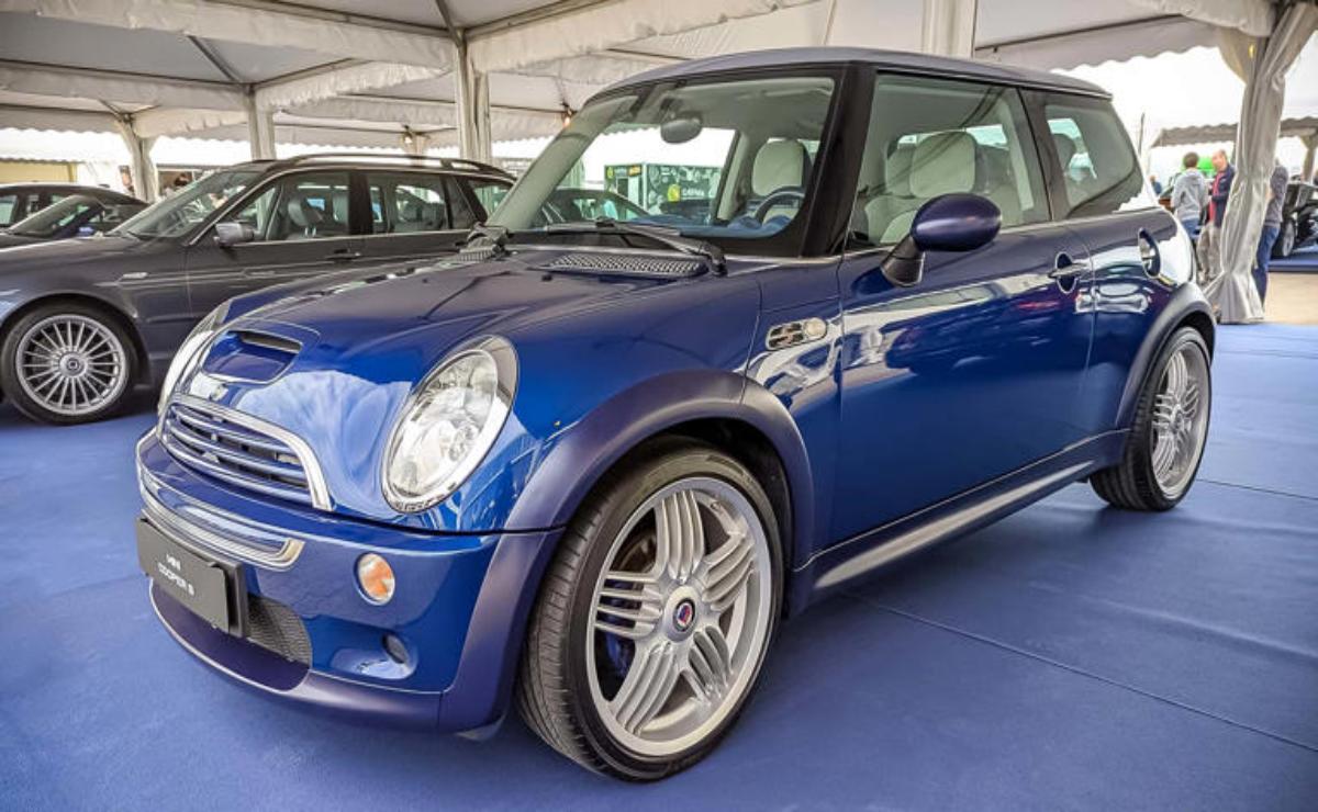 A shiny blue Mini Cooper parked indoors with alloy wheels.