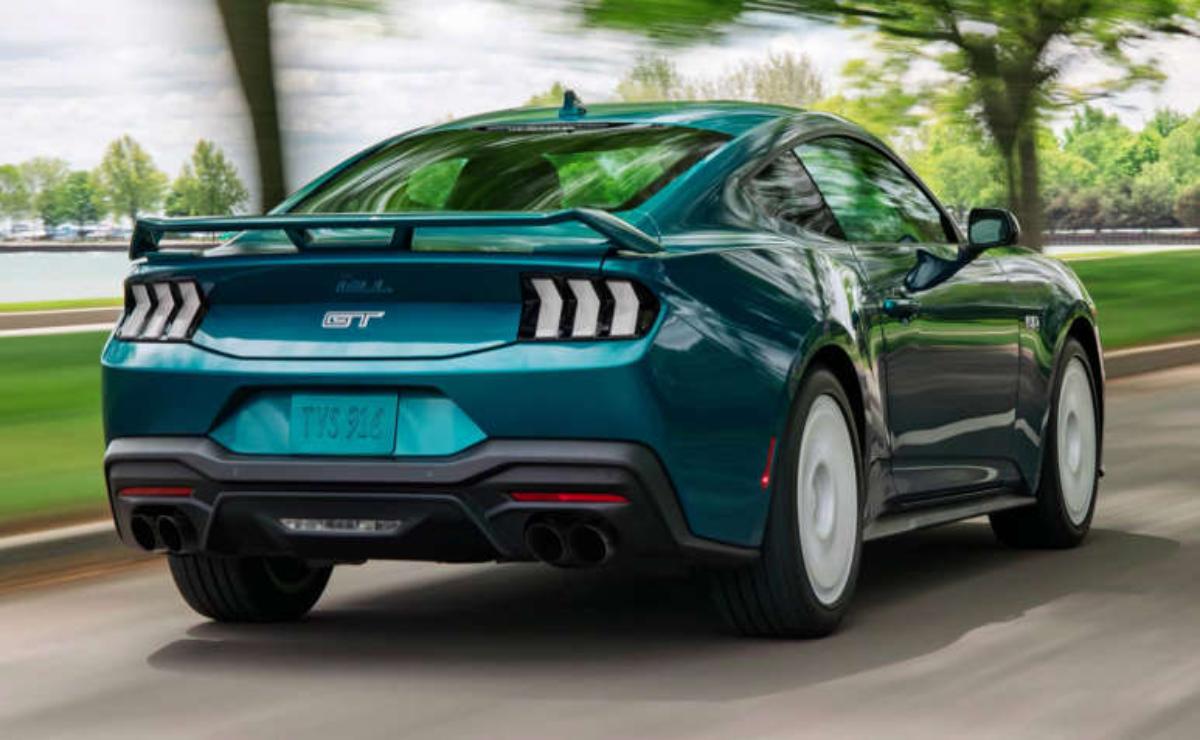 A blue Ford Mustang GT driving near a water body.