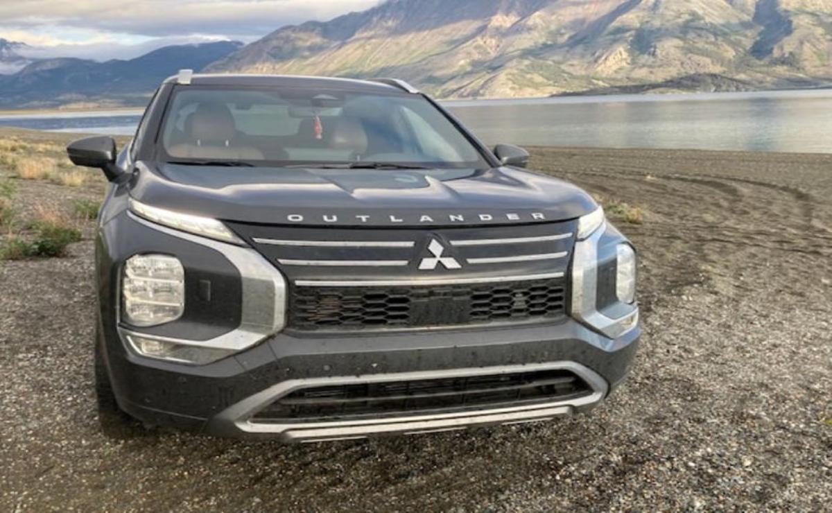 Black Mitsubishi SUV parked near a lake with mountains in the background.