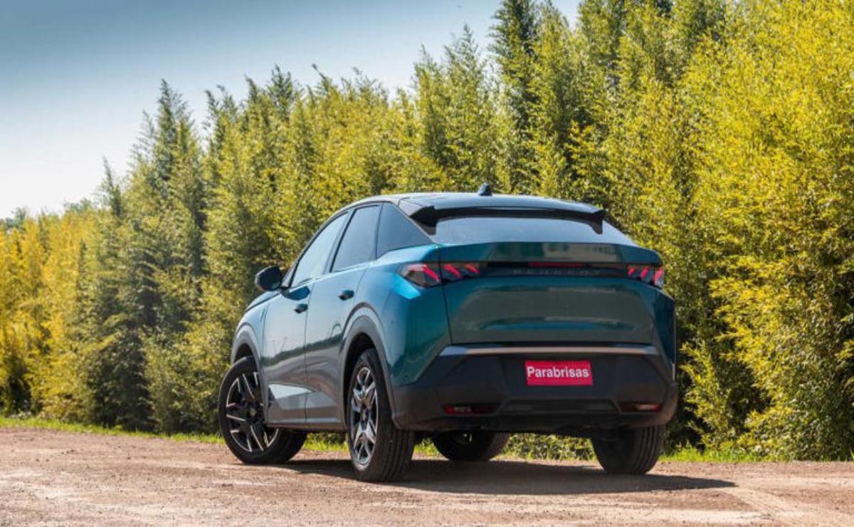 A sleek blue SUV parked on a dirt road surrounded by tall green trees.