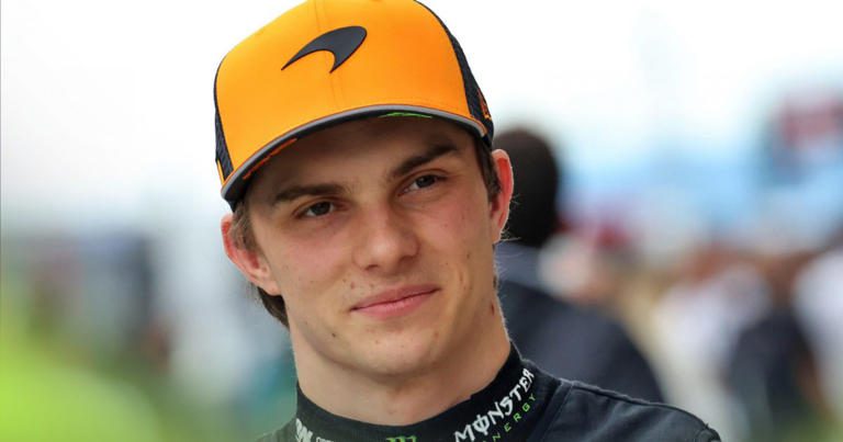 Young man in a yellow cap and black sports attire, smiling slightly.