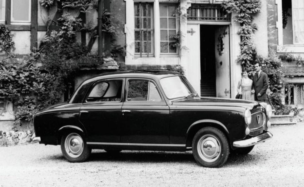 A vintage black and white photo of a classic car parked outside a charming house.