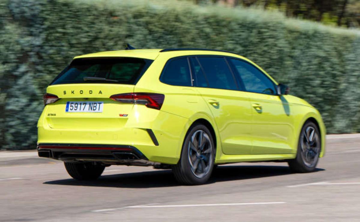 A bright yellow sports hatchback car driving on a road.