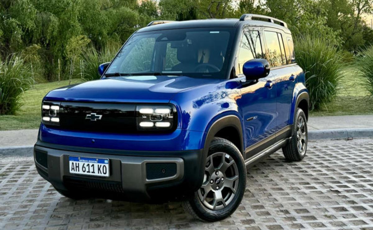 Blue compact SUV parked on a stone driveway with greenery in the background.