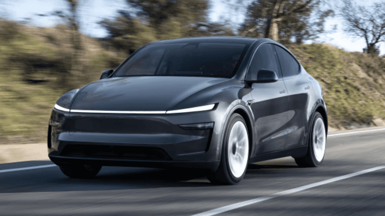 A sleek black electric car driving on a road with blurred background.