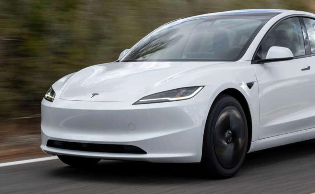 A white Tesla Model Y driving on a road with blurred background.