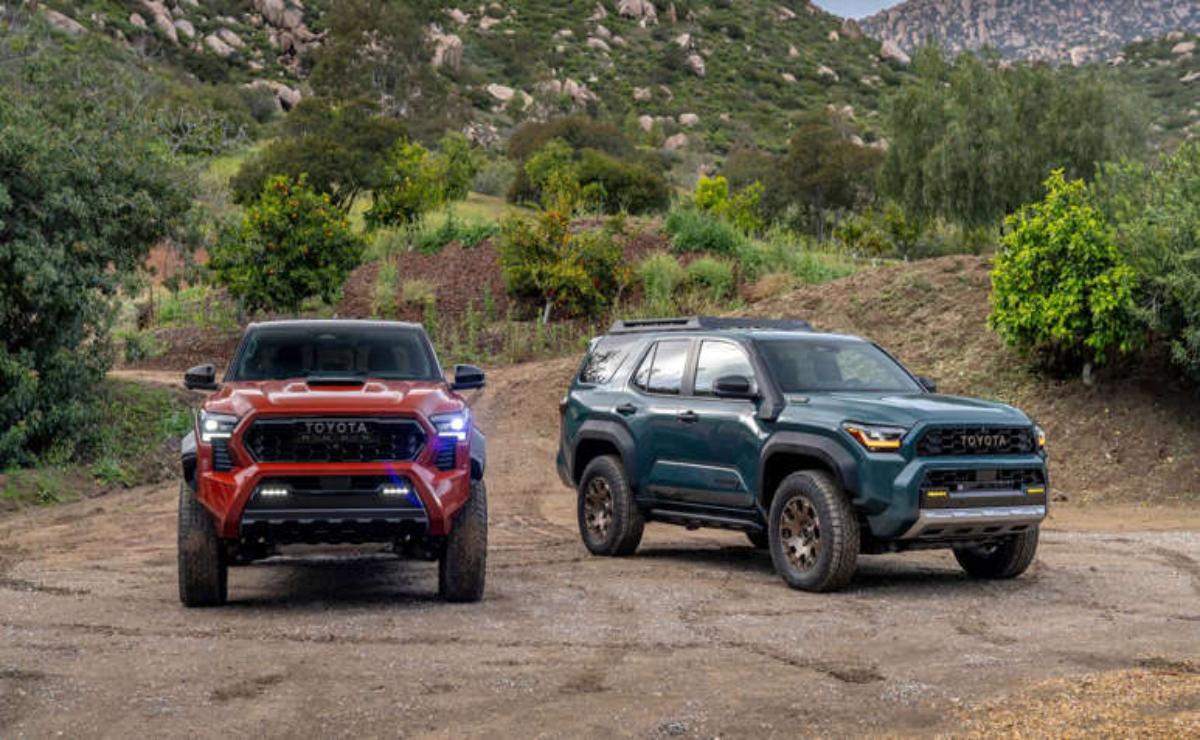 Two rugged SUVs parked on a dirt road with mountains in the background.