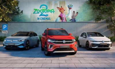 Three Volkswagen cars parked in front of a ZooPia movie billboard.