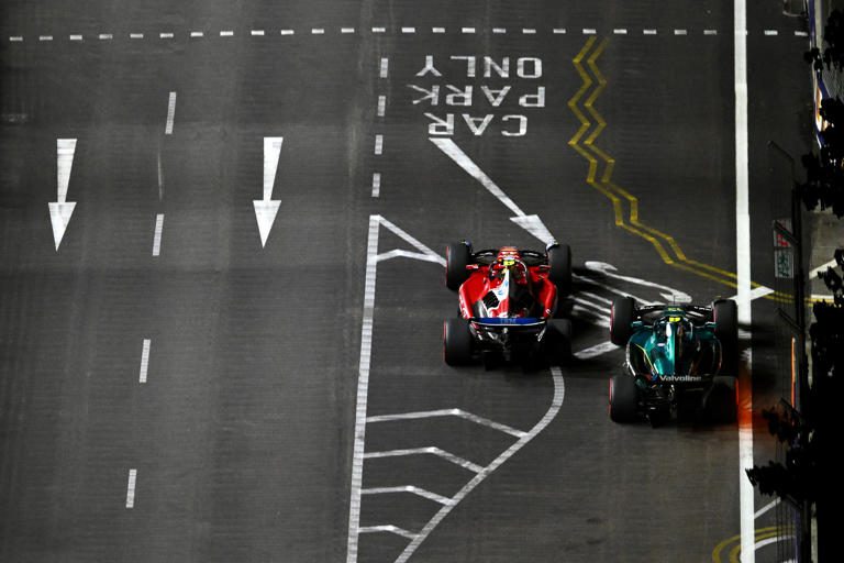 Two Formula 1 cars racing closely on a track.