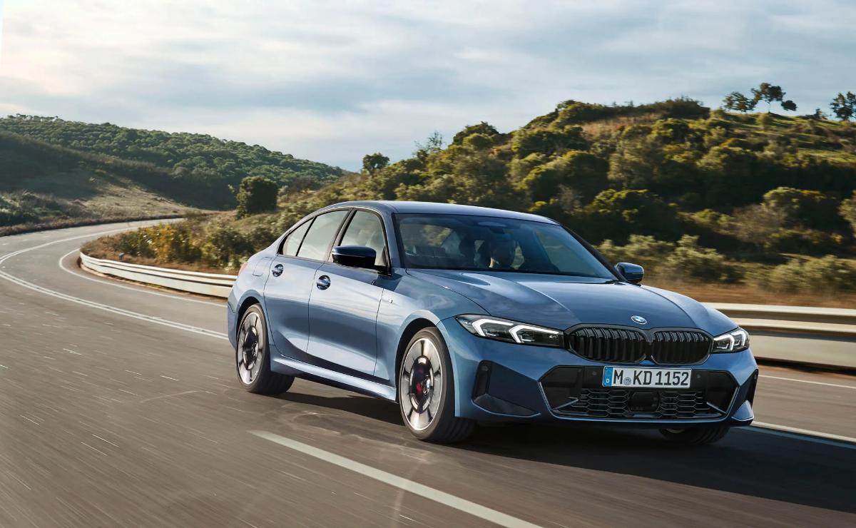 A sleek blue sports sedan driving on a scenic road.