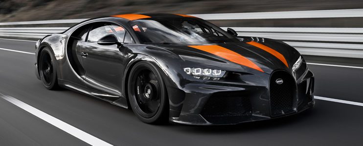 Sleek black and orange sports car speeding on a road.