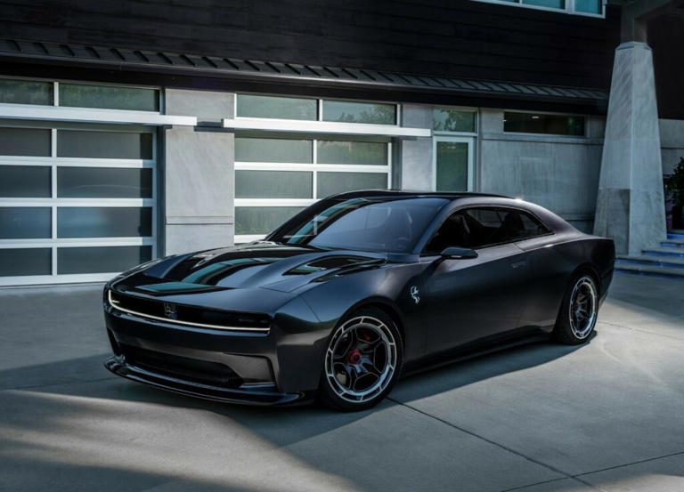 A sleek black sports car parked in front of a modern garage.