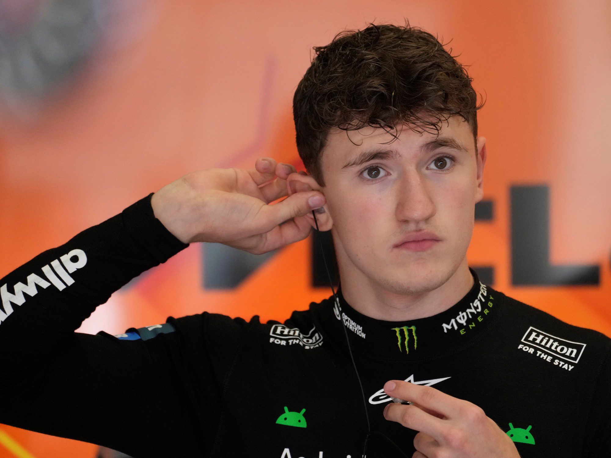 Young male race car driver adjusting his earplug.