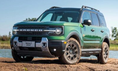 Green Ford Bronco parked on dirt under clear sky.