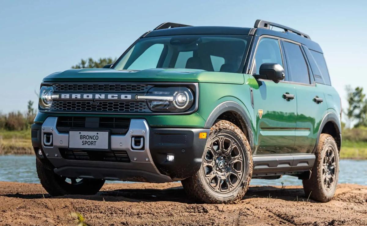 Green Ford Bronco parked on dirt under clear sky.