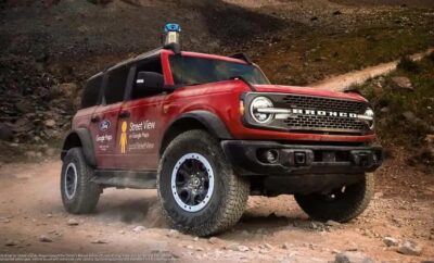 Red off-road rescue vehicle driving on rocky terrain.