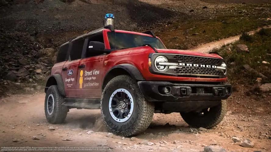Red off-road rescue vehicle driving on rocky terrain.