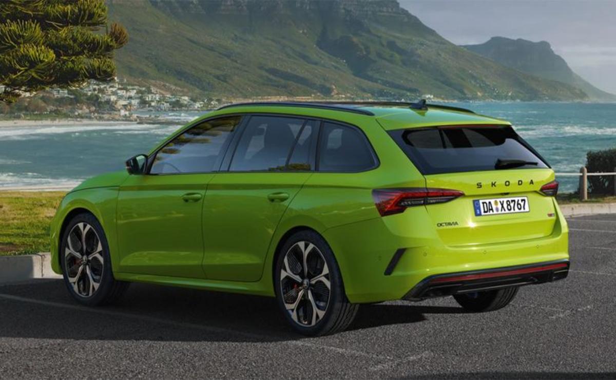 A green station wagon parked with mountains in the background.
