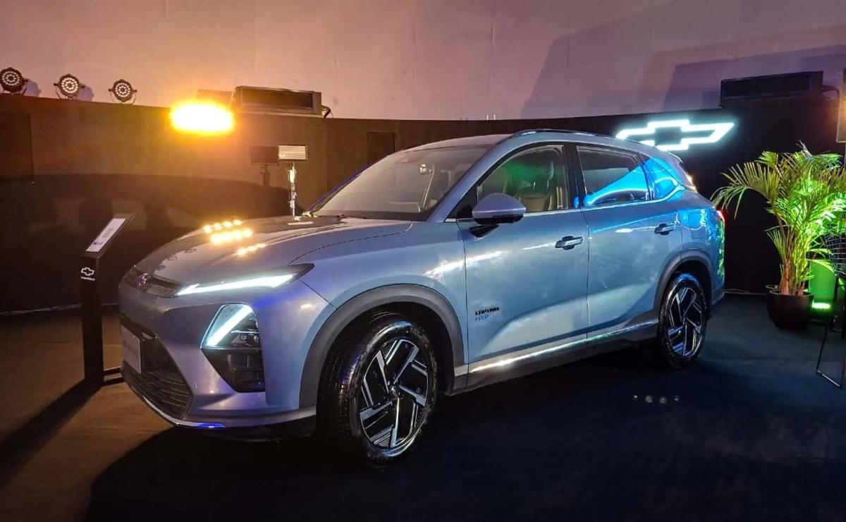 A sleek blue SUV parked at night with illuminated headlights.