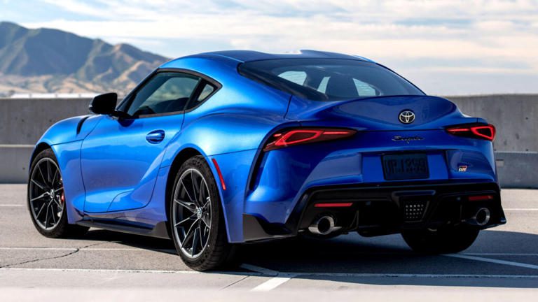 Sleek blue sports car parked against a scenic mountainous backdrop.