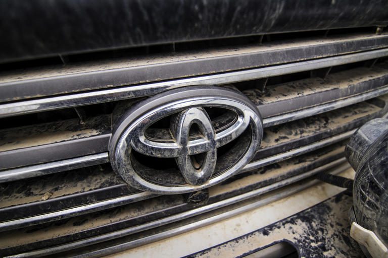 Close-up of a dirty Toyota car emblem and grille.