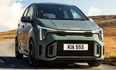 A sleek Kia electric car driving on a road with a clear sky.