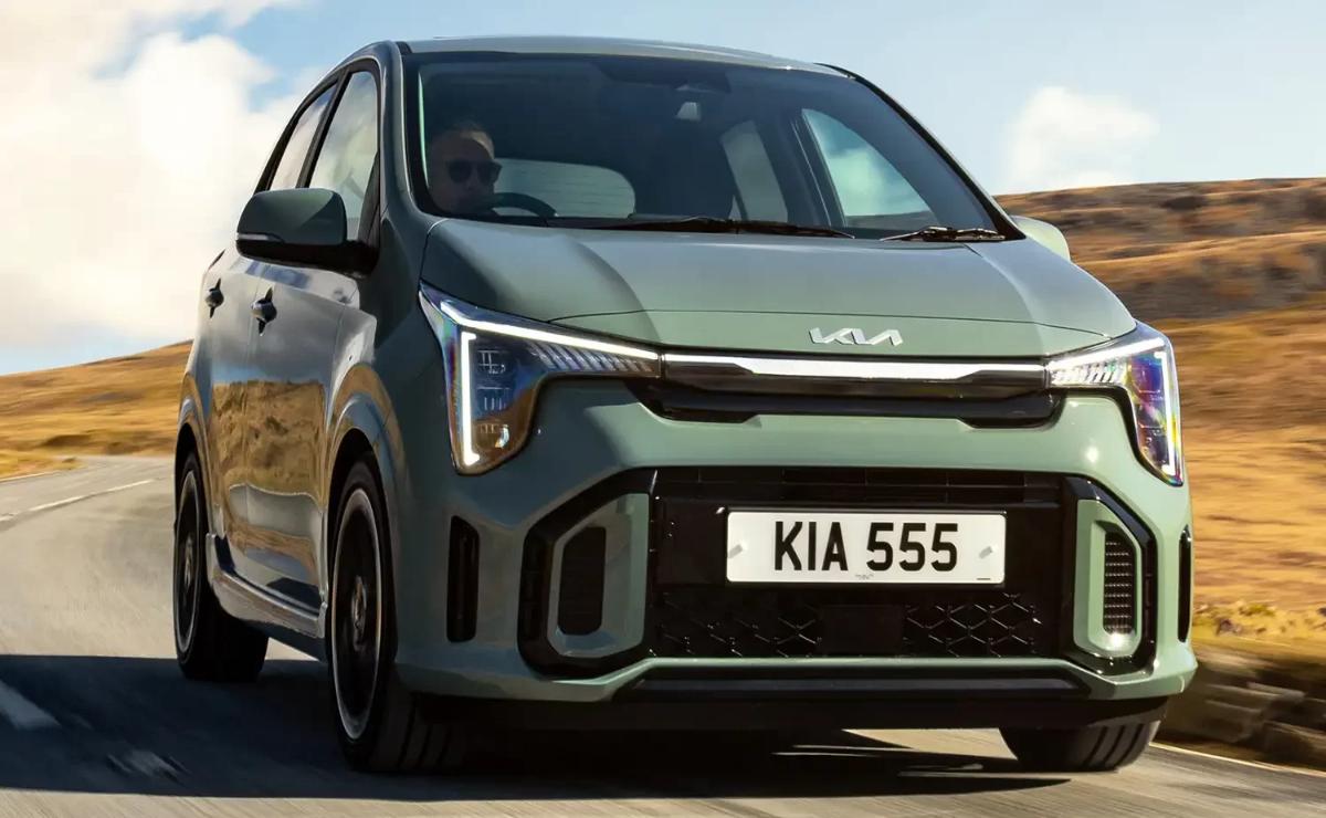 A sleek Kia electric car driving on a road with a clear sky.