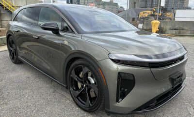 Sleek gray electric SUV parked on city street under overcast sky.