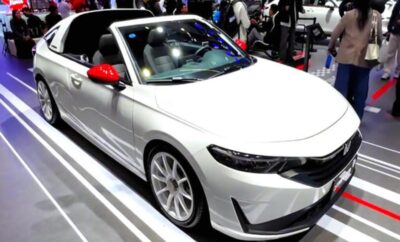 Sleek white convertible car displayed at an auto show.