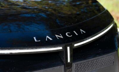 Close-up of a Lancia car emblem on a dark vehicle.