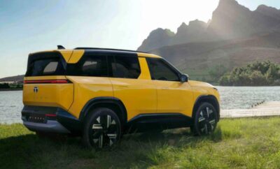 Yellow SUV parked on grassy terrain with mountains in the background.