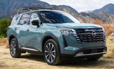 Modern green SUV parked with mountains in the background.