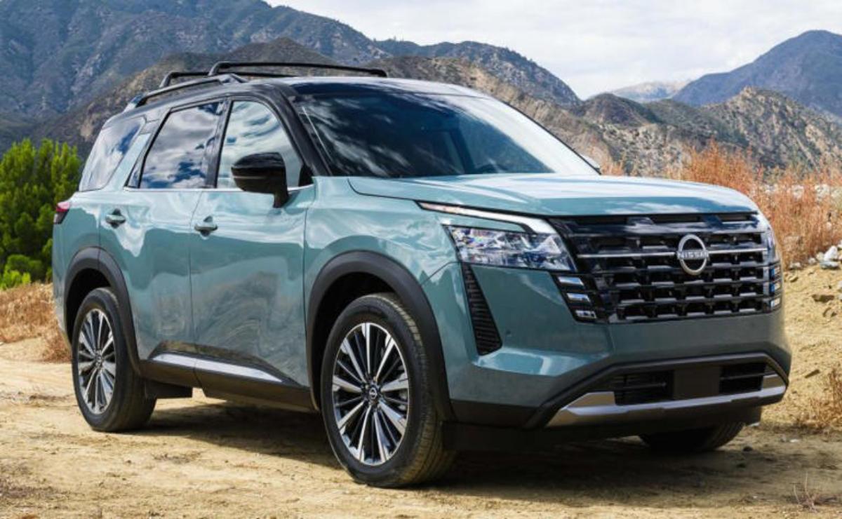 Modern green SUV parked with mountains in the background.