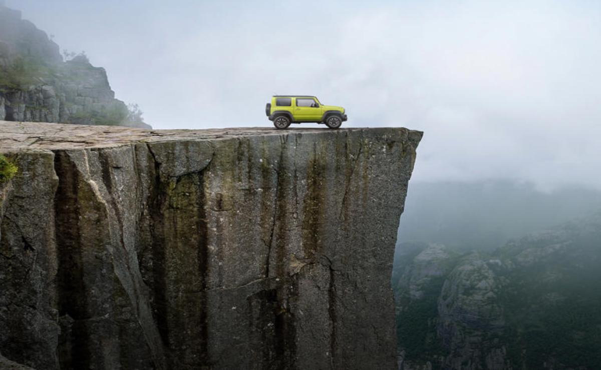 A yellow SUV parked near the edge of a steep cliff.