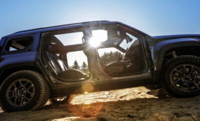 Black SUV with open doors on a sandy terrain during sunset.