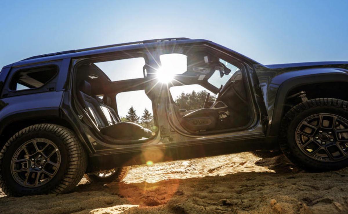 Black SUV with open doors on a sandy terrain during sunset.