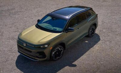 Sleek green SUV parked on a paved surface under sunlight.