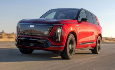 Sleek red electric SUV driving on road at sunset.