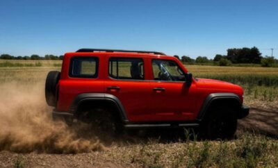 A red off-road vehicle kicking up dirt on a rugged trail.