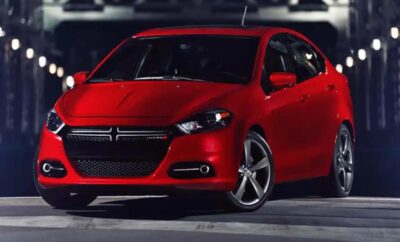 Red modern sedan parked in an urban setting at night.
