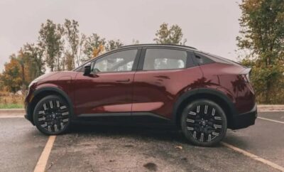 Side view of a sleek maroon SUV with black wheels parked outdoors.
