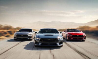 Three powerful sports cars racing on an open road with mountains in the background.